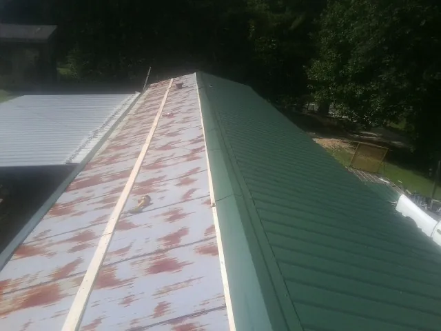 Old rusted panels beside newly installed green metal roofing — Wind Damage Roof Repair by Roofing Brothers in Astor