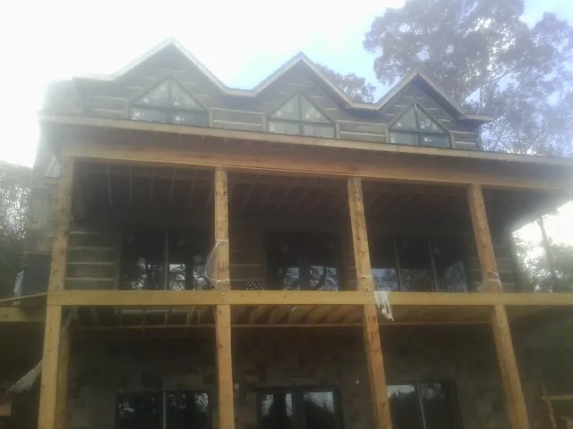 Dormers and porch framing on a large log home under construction — Roof Coating work by our crew in Astor