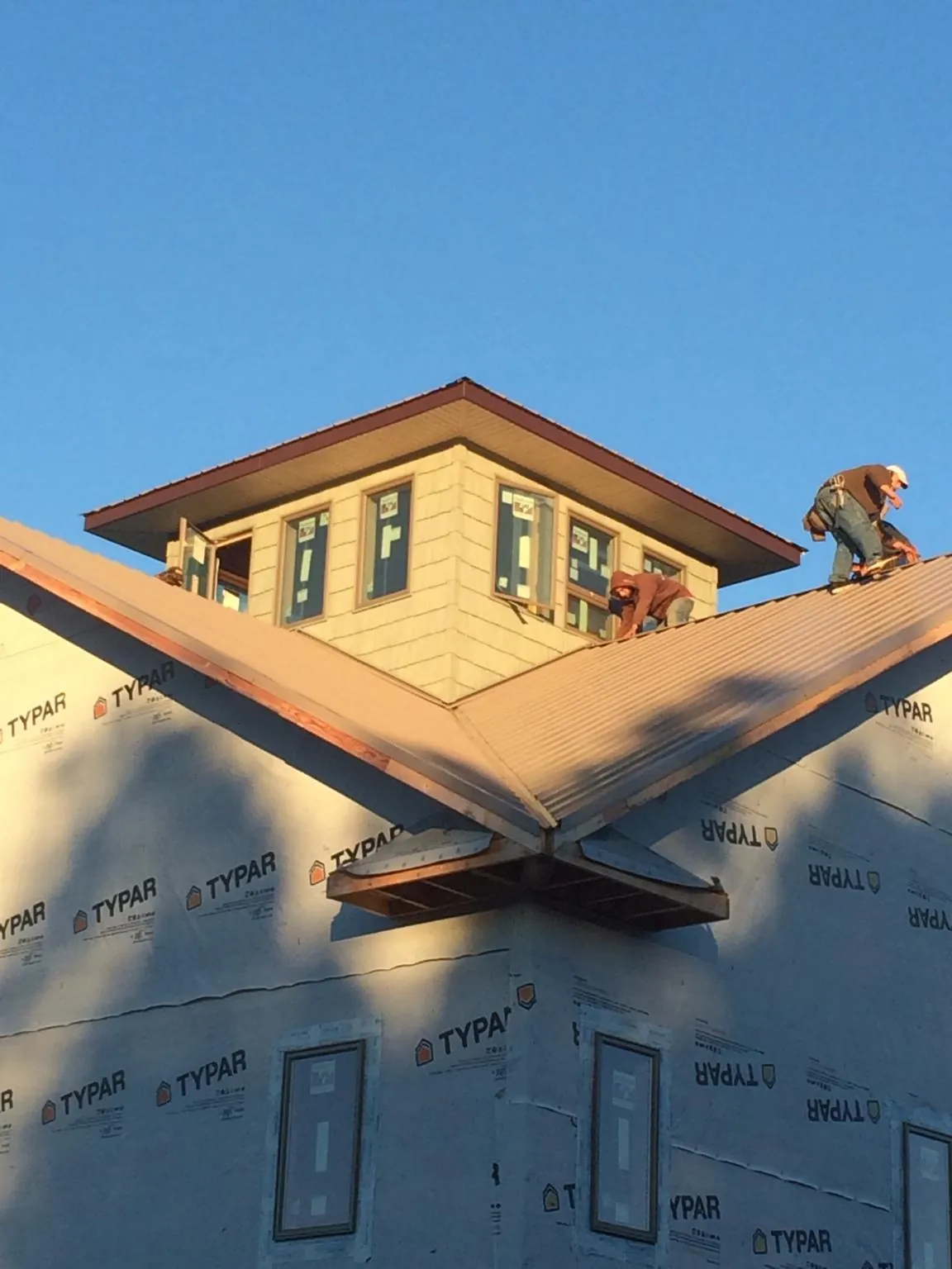 Roofers working around a rooftop cupola on a new metal roof at sunset — Roof Waterproofing in Astor by Roofing Brothers